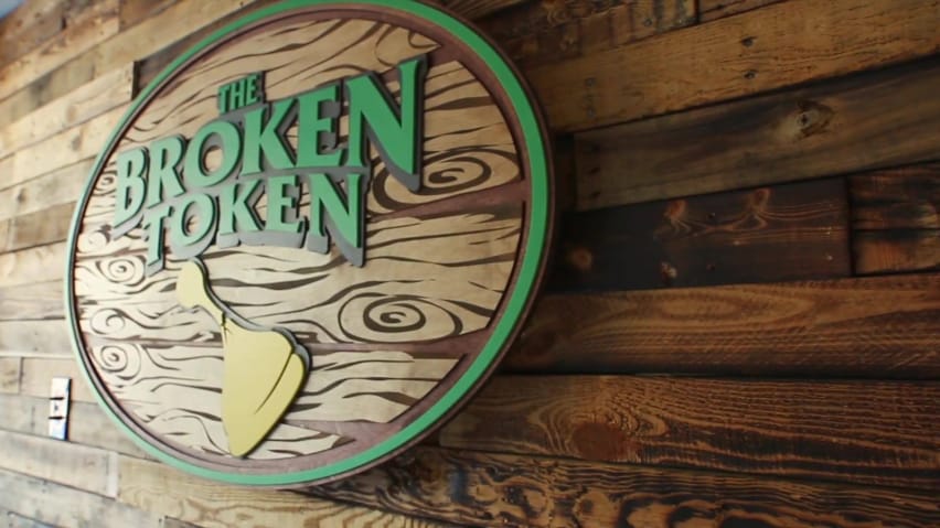 Logoya Broken Token li ser lewheyek darîn li dîwarekî daleqandî ye