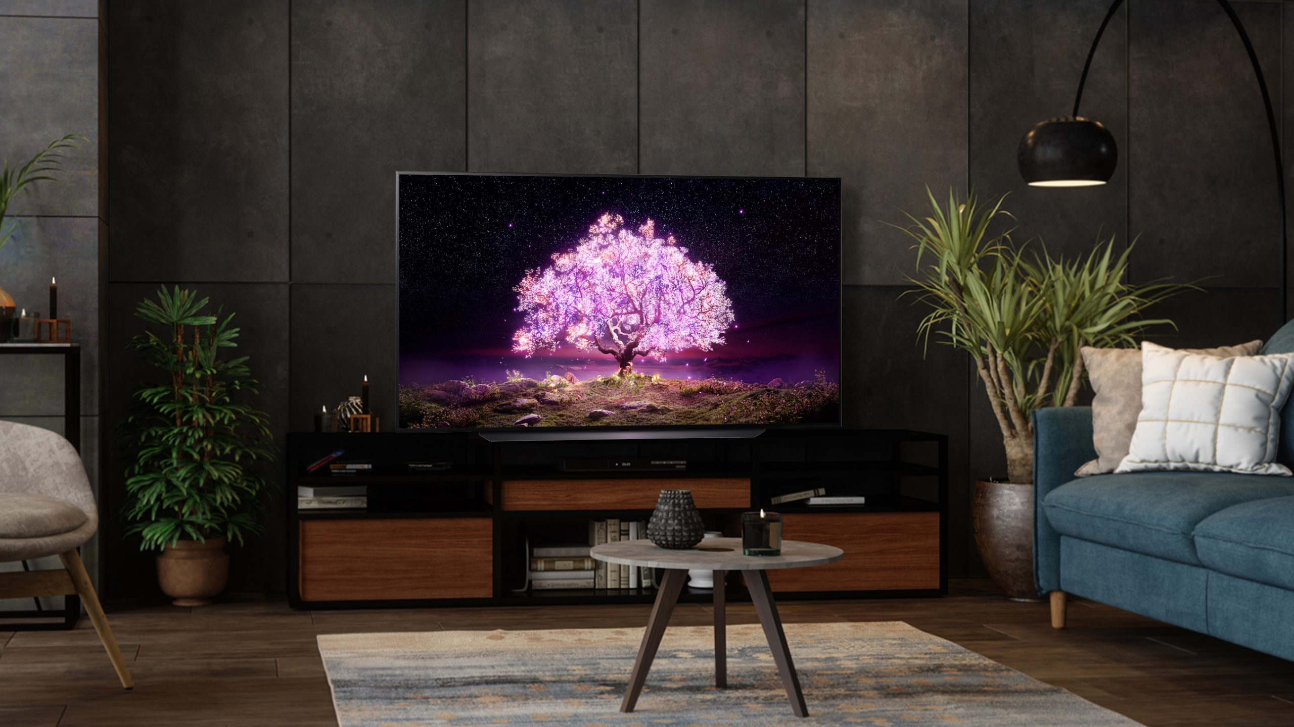 LG C1 OLED nunha sala de estar escura nun soporte de televisión e rodeada de sofás e plantas