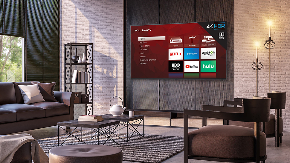 TCL 6-Series montado na parede nunha sala de estar e mostrando o sistema operativo do televisor