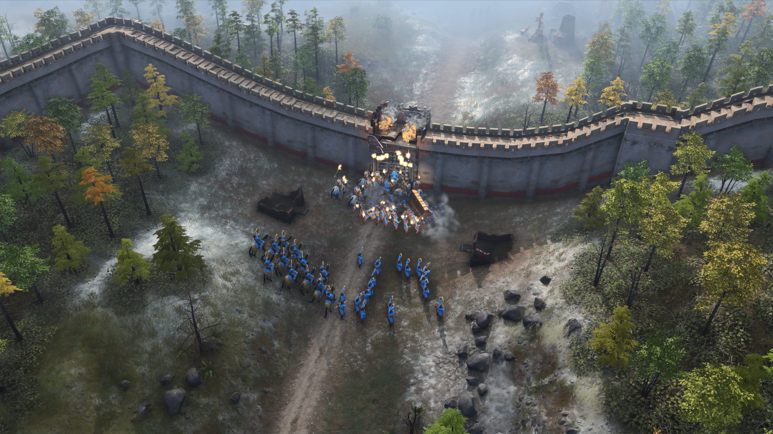Tentara Age of Empires IV menyerang gerbang batu kota musuh