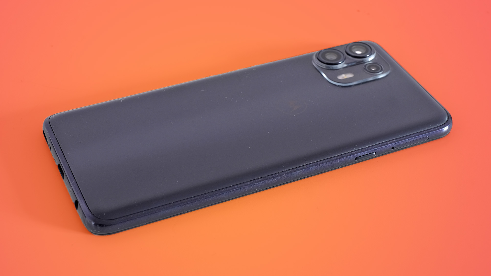 En Motorola Edge 20 Lite från baksidan mot en orange bakgrund