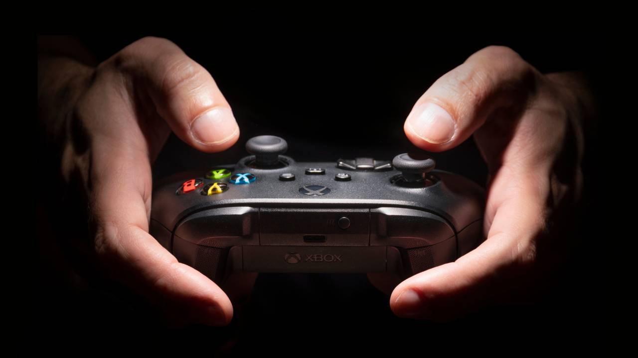 Марде дар торикӣ контроллери Xbox Series X-ро дар даст дорад